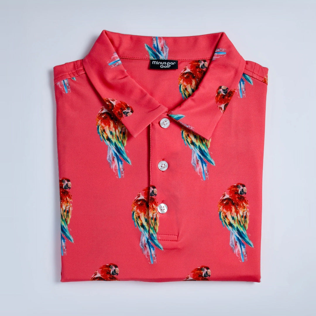 Parrot golf polo in coral with a rainbow parrot print, folded
